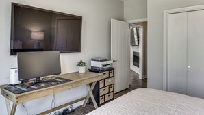 A bedroom with a bed, a desk with a computer, a lamp, and a potted plant. - Modern Lake House with Beautiful Shoreline (Frankston)