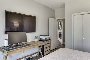 A bedroom with a bed, a desk with a computer, a lamp, and a potted plant. - Modern Lake House with Beautiful Shoreline (Frankston)