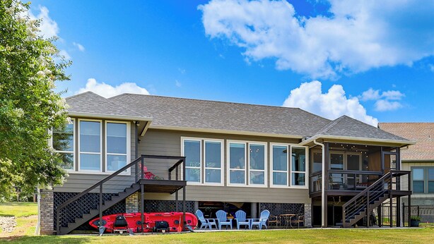 A two-story house with a covered patio, a staircase, and a red vehicle parked outside. - Modern Lake House with Beautiful Shoreline (Frankston)