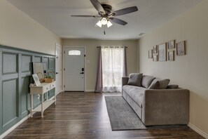A room with a ceiling fan, a sofa, a console table, and a door with a decorative glass panel. - 4 Mi to Dtwn: Garland Getaway w/ Fenced-In Yard (Garland)