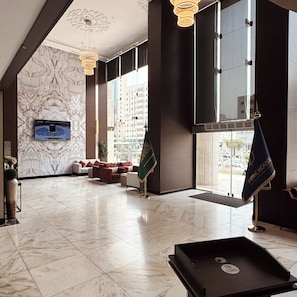 A spacious lobby with a marble floor, a television mounted on the wall, and a seating area with sofas. - Park Elite Hotel (Makkah)