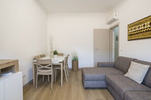 A compact living space with a dining area, a sofa, and a small kitchenette. - GuestHost - Cozy Apartment with Balcony (Como)