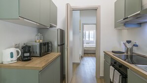 Et lille køkken med mikroovn, elkedel og køleskab.