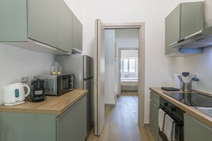 Eine kleine Küche mit Mikrowelle, Wasserkocher und Kühlschrank.