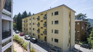 En flereetagers boligbygning med altaner, parkeringsplads og udsigt til gaden.