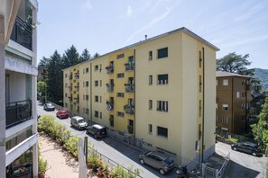 Ein mehrgeschossiges Wohngebäude mit Balkonen, einem Parkplatz und Blick auf die Straße.