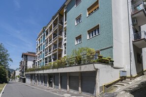 A multi-story residential building with balconies, a garage, and a clear sky. - GuestHost - Cozy Apartment with Balcony (Como)