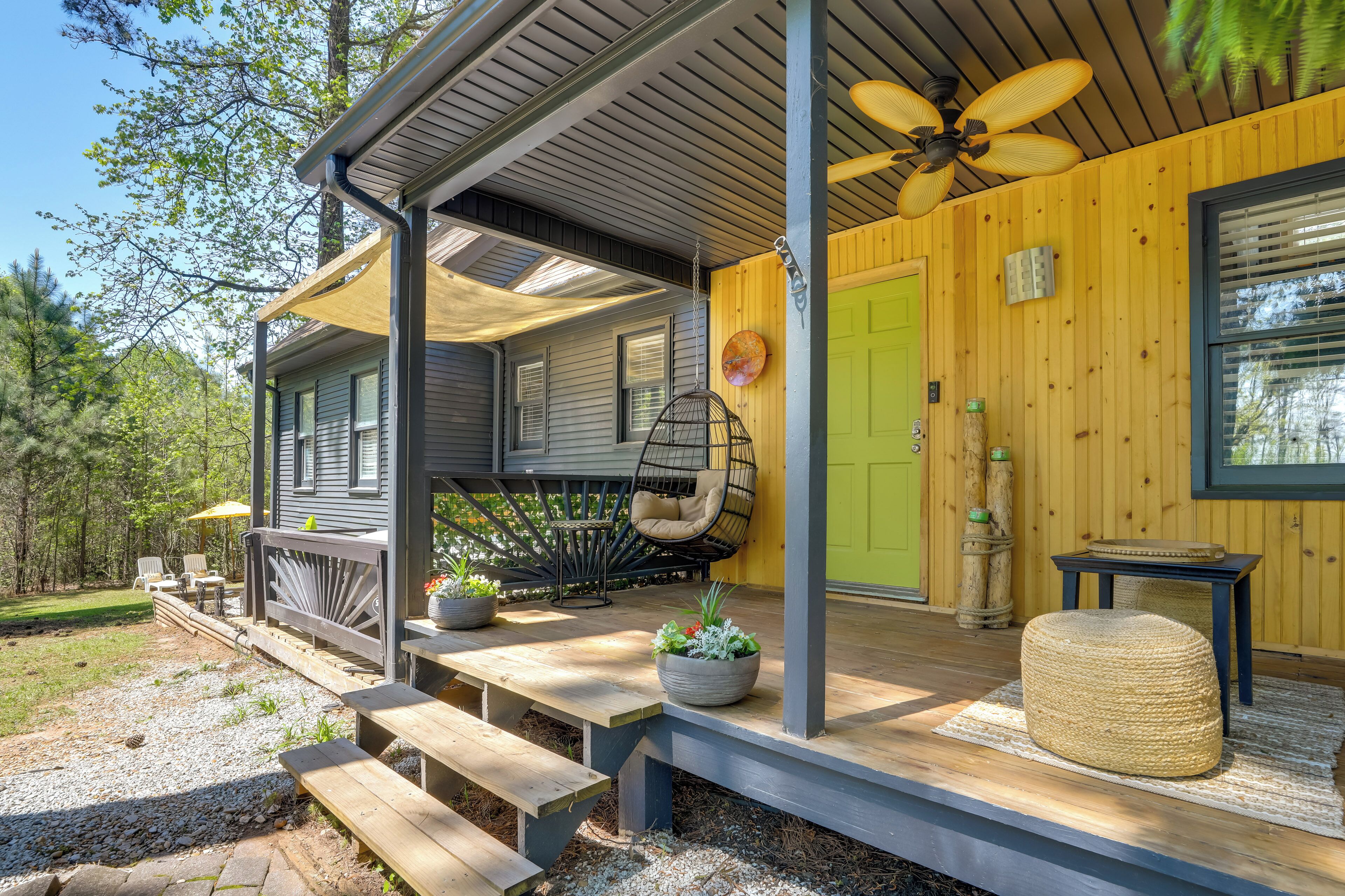 Una terraza de madera con mobiliario exterior, un ventilador de techo y una puerta verde.