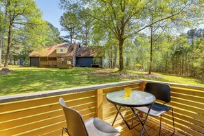 Una terraza de madera con una mesa y sillas, con vistas a un jardín y una casa.