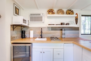 A compact kitchen with a microwave, coffee maker, and a small refrigerator. There are decorative plates on shelves above the counter. - Group Entertainment Oasis! 3-Unit Lithonia Getaway (Lithonia)