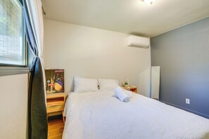 A neatly made bed with white linens, a bedside lamp, and a poster on the wall. - 3 Mi Dtwn! Eugene Family Retreat w/ Yard & Patio (Eugene)