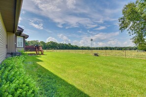 A grassy yard with a wooden bench, a fence, and a house. - Peaceful Fulton Farm Retreat w/ Outdoor Space! (Fulton)