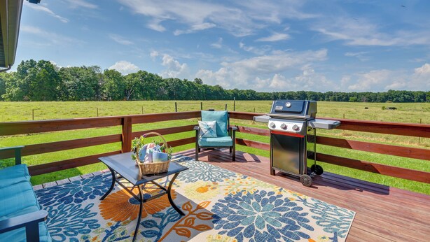 Una terraza al aire libre con una parrilla, una mesa con una cesta y una silla.