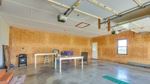 Una habitación amplia con techo alto, paredes de madera a la vista, suelo de hormigón, una mesa con sillas y un proyector montado en el techo.