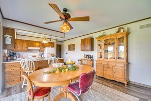 A kitchen with wooden cabinets, a dining table with chairs, a ceiling fan, and a chandelier. - Peaceful Fulton Farm Retreat w/ Outdoor Space! (Fulton)