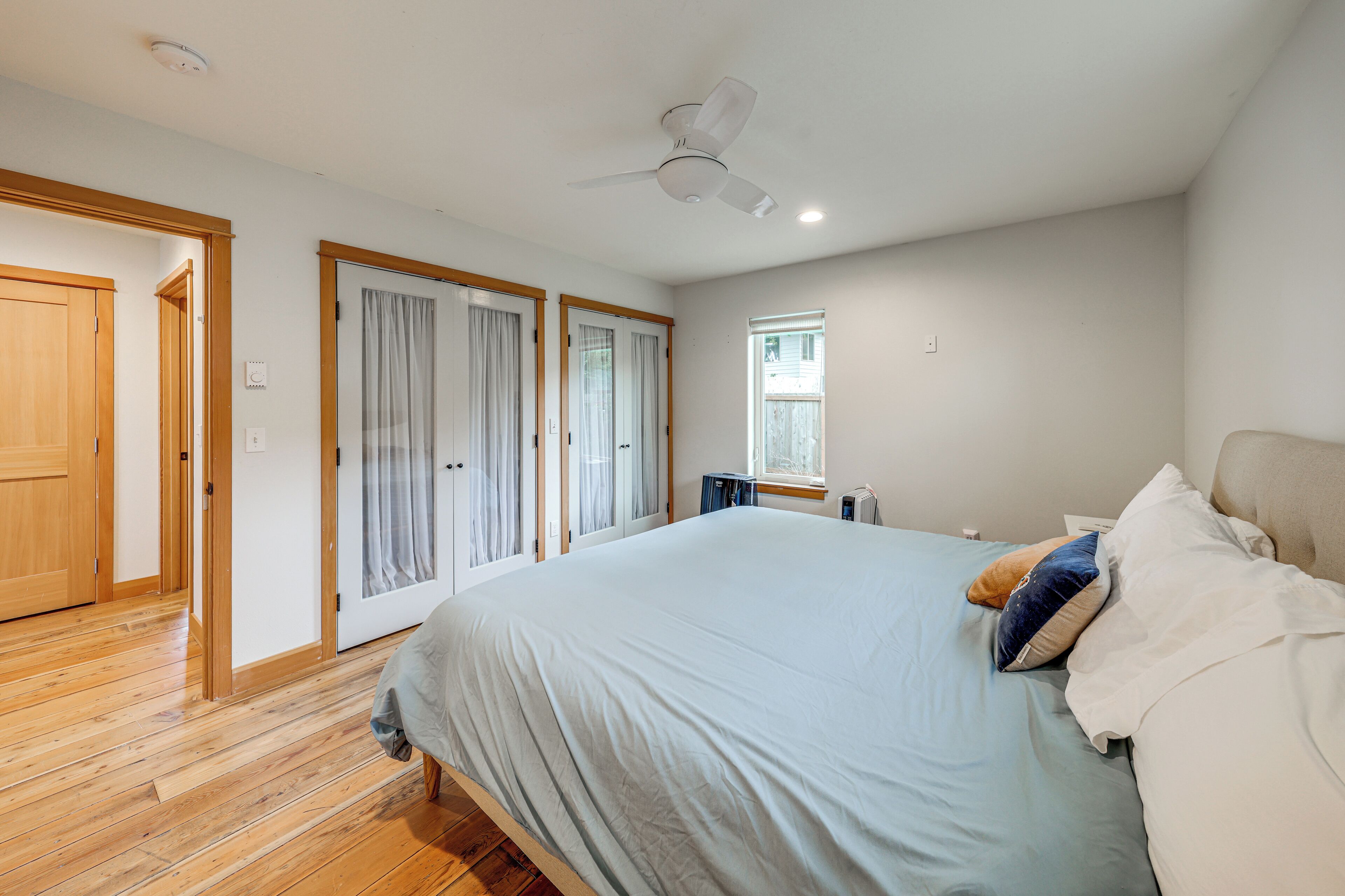 Un dormitorio con una cama, ventilador de techo y ventana.