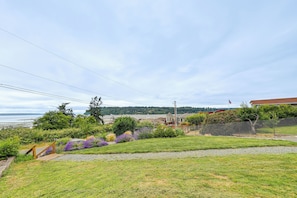 A residential property with a view of the water, a wooden deck, and a fenced garden area. - Hot Tub & Puget Sound View! Whidbey Island Retreat (Clinton)