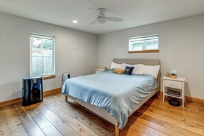 Une chambre à coucher avec un lit, une table de chevet, une fenêtre et un ventilateur de plafond.