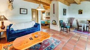 A living room with a blue sofa, wooden coffee table, and a mounted animal head. - Traditional Taos Adobe Casita: Comfortable & Quiet (Taos)