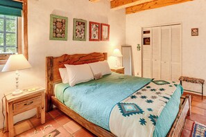 A bedroom with a wooden bed, two bedside tables, a window with a view, and a wardrobe. - Traditional Taos Adobe Casita: Comfortable & Quiet (Taos)