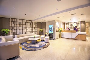 A modern hotel lobby with a reception desk, seating area, and a television screen. - Cozzet Yashobhoomi Dwarka (New Delhi)