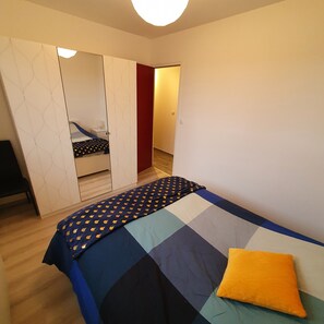 Un dormitorio con cama, armario y espejo.