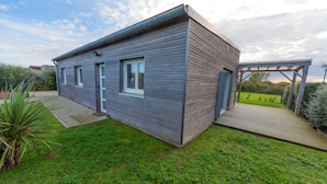 A modern house with a wooden exterior, a front door, and a small porch. - LA MAISON DES DUNES, sleeps 7, near the sea (Les Moitiers-d'Allonne)