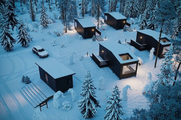 Un conjunto de cabañas modernas cubiertas de nieve, con varias construcciones, cada una con amplios ventanales y un diseño minimalista.