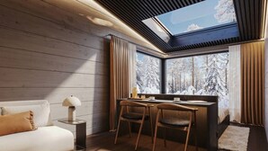 Ein gemütliches Zimmer mit Holzvertäfelung, einem Sofa, einem Schreibtisch mit zwei Stühlen und einem Oberlicht.