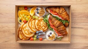 A breakfast box containing pancakes, croissants, fresh fruit, and yogurt. - Aurora Roof Window | 28m² Private Lux Arctic Cabin (Rovaniemi)