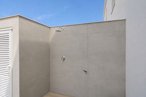 Eine Eckdusche mit Fliesenwand und Holzboden.