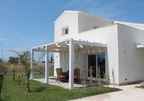 Una casa moderna con un porche cubierto, césped y cielo despejado.