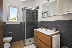 A modern bathroom with a glass shower enclosure, a white sink, and a wooden vanity. - Villa in Caucana with 2 bedrooms sleeps 4 (Caucana)