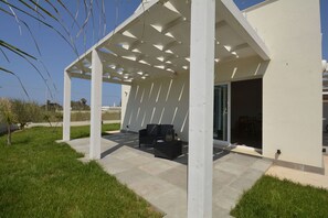 Un área de estar al aire libre con techo y una pérgola, una mesa de patio y sillas.