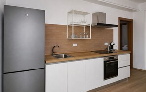 Eine moderne Küche mit einem Edelstahl-Kühlschrank, einem Einbauofen und einer Kaffeemaschine.