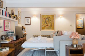 A bedroom with a bed, bedside table, lamp, and artwork on the wall. - Farmhouse Chic Studio Flat with Private Garden (Greater London)