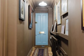 A hallway with a blue door, framed pictures on the walls, and a patterned rug on the floor. - Farmhouse Chic Studio Flat with Private Garden (Greater London)