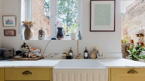 A kitchen with a sink, window, and various kitchen items. - Farmhouse Chic Studio Flat with Private Garden (Greater London)
