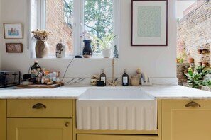 A kitchen with a sink, window, and various kitchen items. - Farmhouse Chic Studio Flat with Private Garden (Greater London)