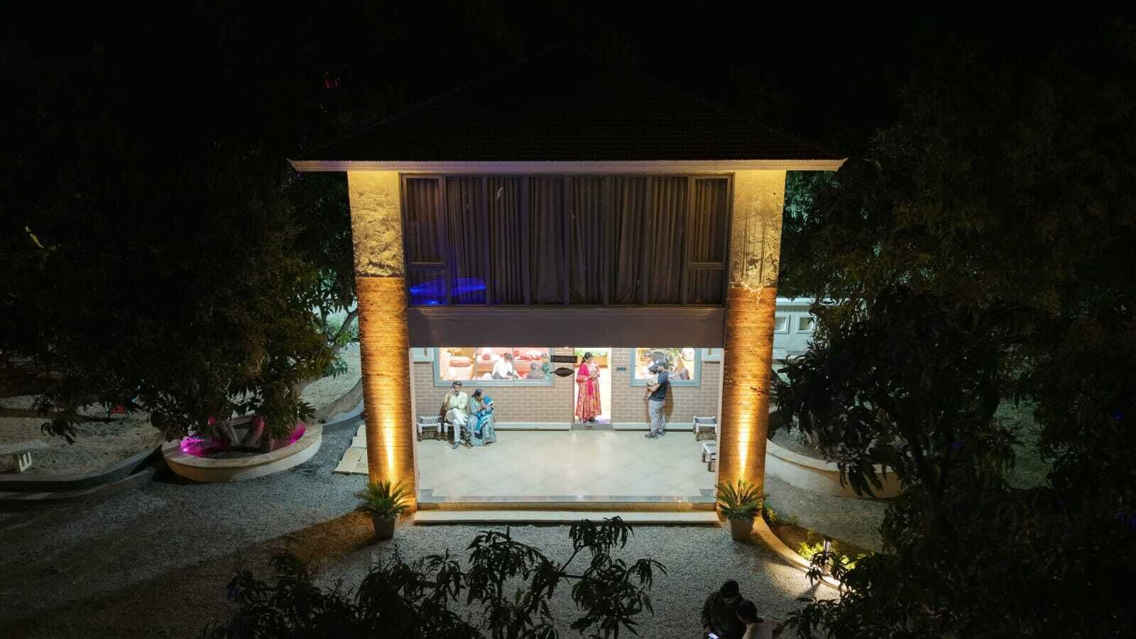 A building with a covered entrance, large columns, and a seating area with people inside.