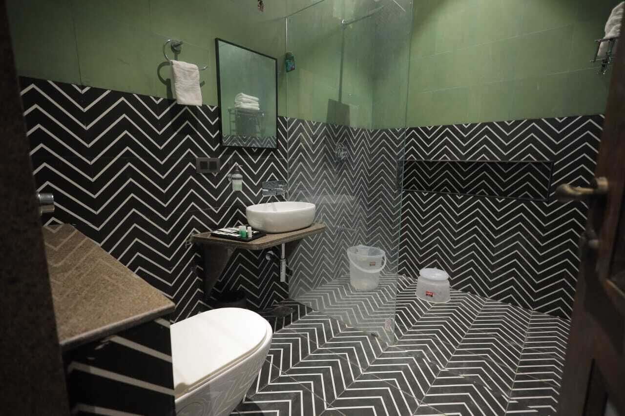 A bathroom with a black and white chevron-patterned floor, a white sink, a mirror, and a toilet.