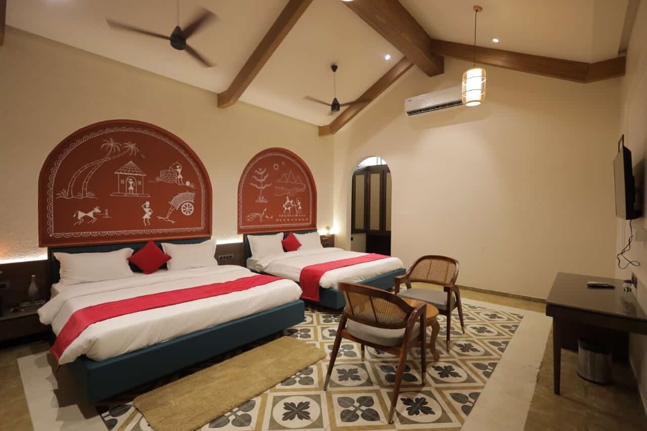 Habitación de hotel con dos camas, un escritorio, una silla, un ventilador de techo y un adorno de pared.