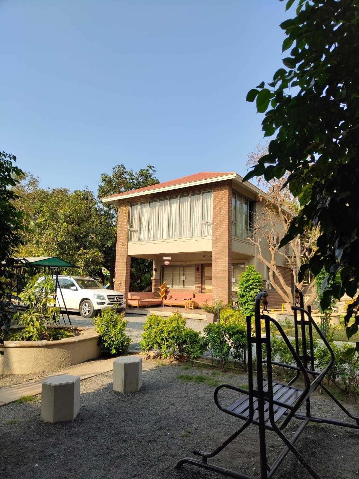 A two-story building with a brick facade, a covered outdoor seating area, and a swing set in the foreground.