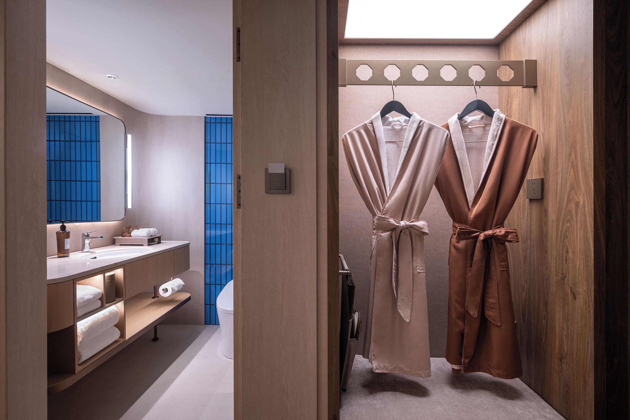 A modern bathroom with a wooden vanity, a mirror, a towel rack, and a shower area.