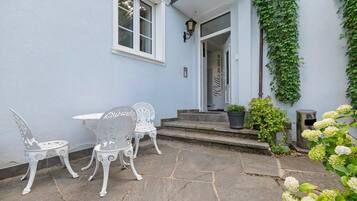 Eine Terrasse mit Tisch, Stühlen, einem Blumentopf und einem Willkommensschild.