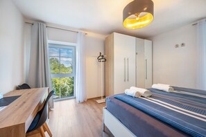 Um quarto com cama, escrivaninha e guarda-roupa.