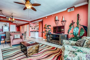 A spacious living room with a ceiling fan, a television, and a large plant. - San Carlos 1208 (Gulf Shores)