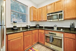 A modern kitchen with wooden cabinets, stainless steel appliances, and a granite countertop. - Resort-style living, heated pool and water slides! (Kissimmee)