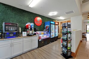 Uma área de quiosques de autoatendimento, com uma máquina de café, um refrigerador de Pepsi e uma máquina de vendas automáticas.