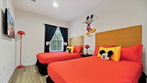 A hotel room with two beds, red bedding, Mickey Mouse wall art, and a red floor lamp. - Remodeled home, Regal Oaks-September Special Price (Kissimmee)